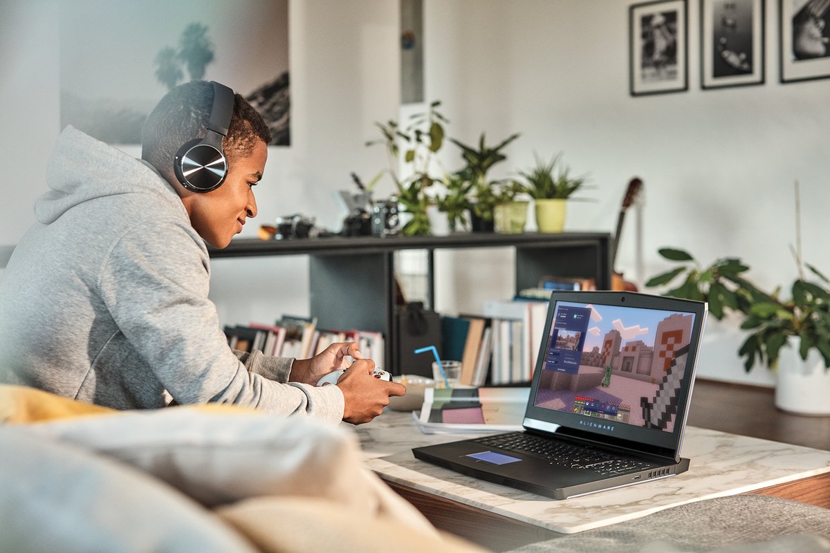A man wearing headphones plays Minecraft on his laptop at home