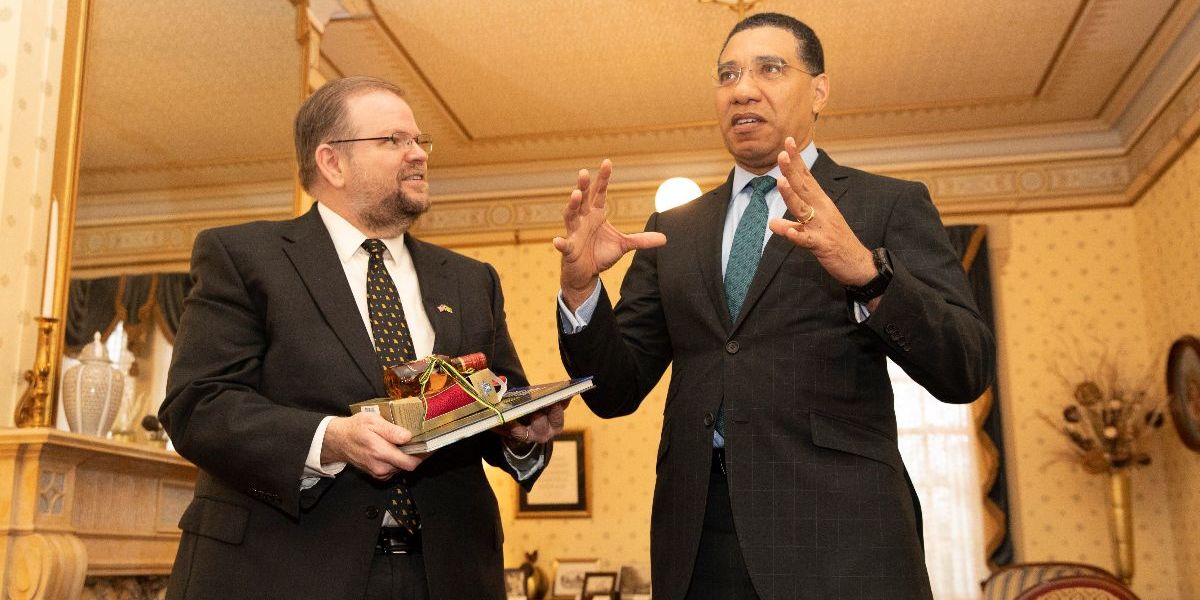 Chancellor Cartwright holds gifts while looking at the Prime Minister talking