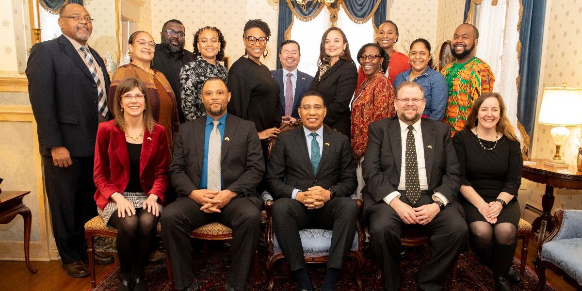 A group of campus leaders and Jamaican leaders sit and stand for a posed photo.