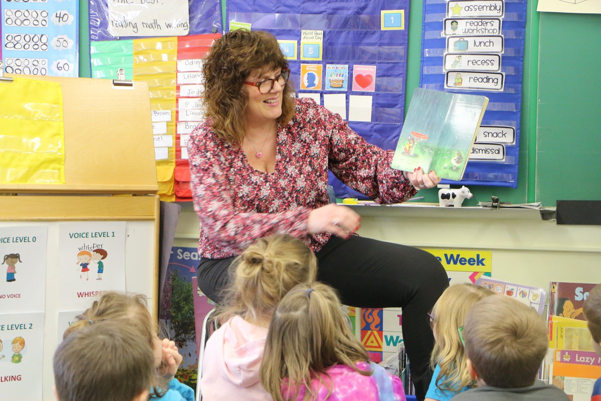 photo shows students listening to a story read by superintendent linda goewey.