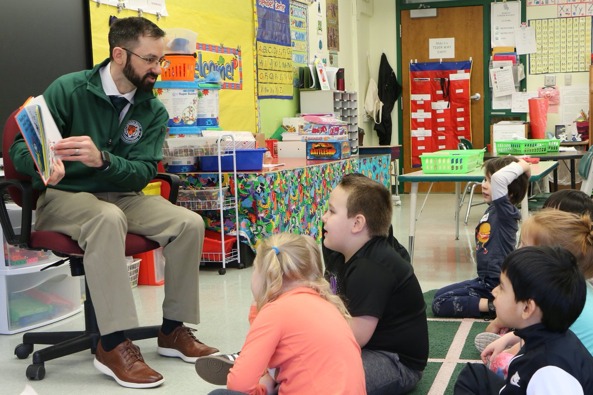 photo shows students seated listening to a story being read by Michael DeCaprio