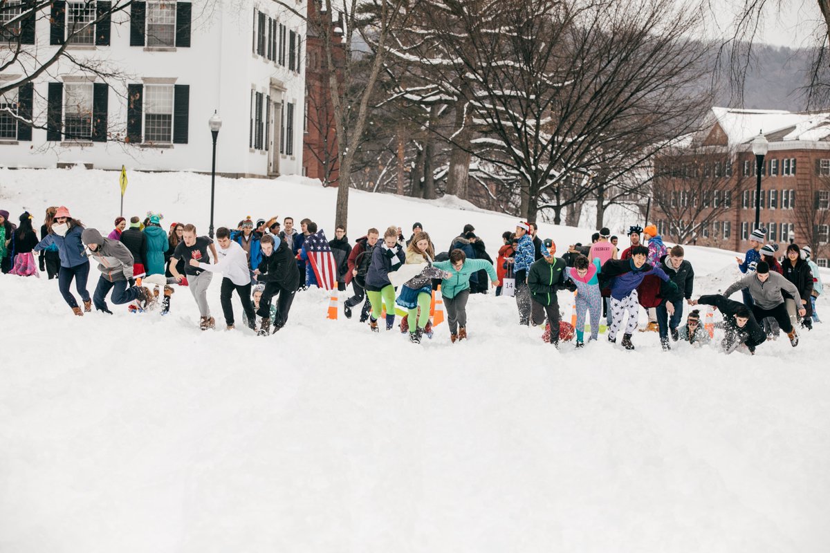 Students and community members run through the snow pulling their friends in a sled race on the Green. 