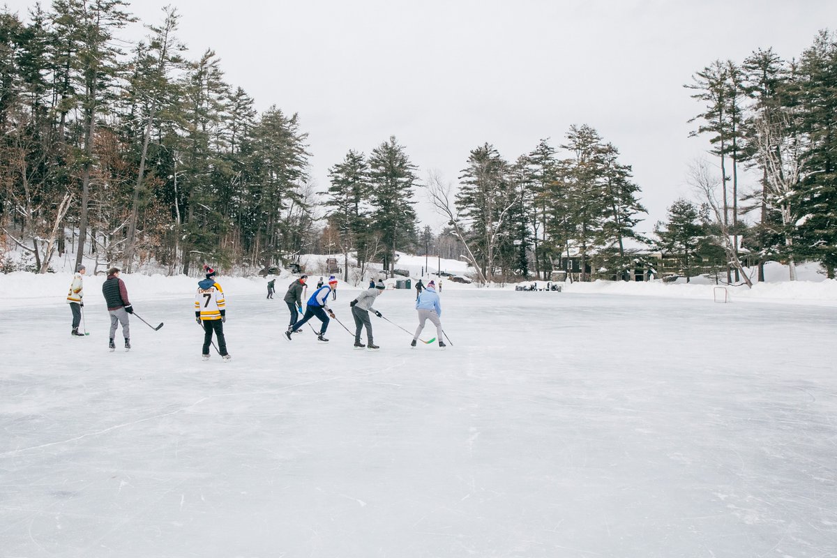 Students play ice hockey on a frozen pond.