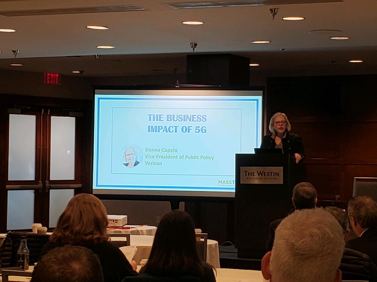 Donna Cupelo stands at podium speaking about the business impacts of 5g. 