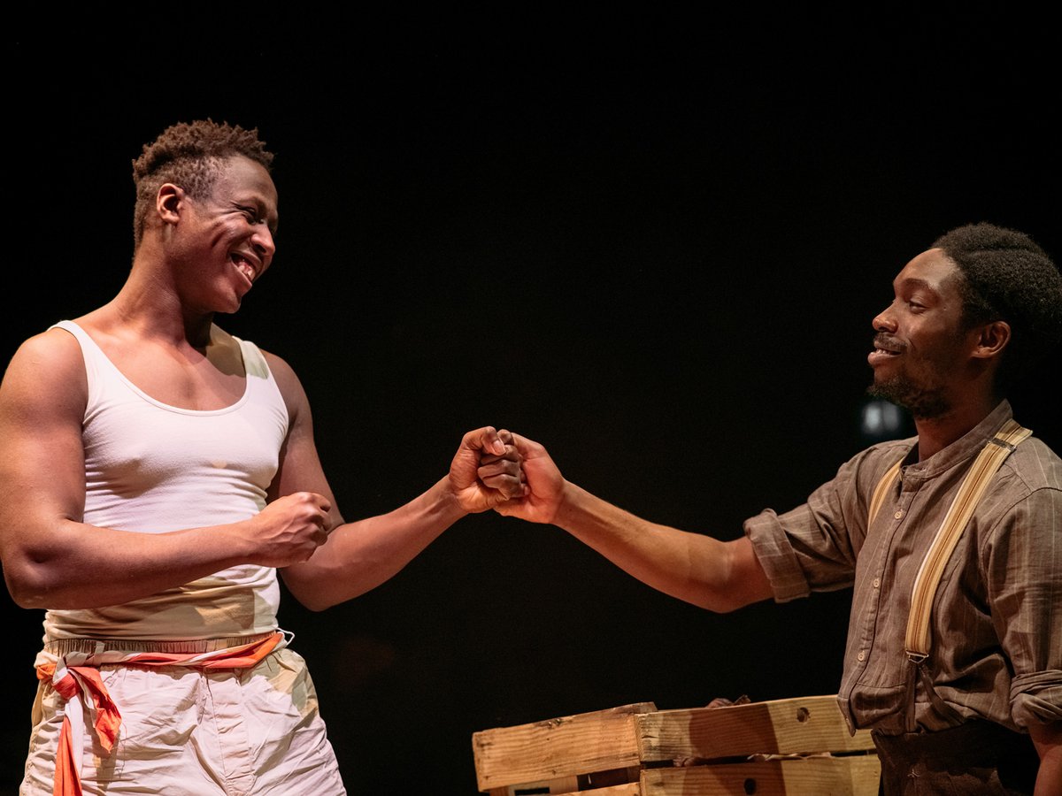 Two actors fist-bumping, one in boxing clothing