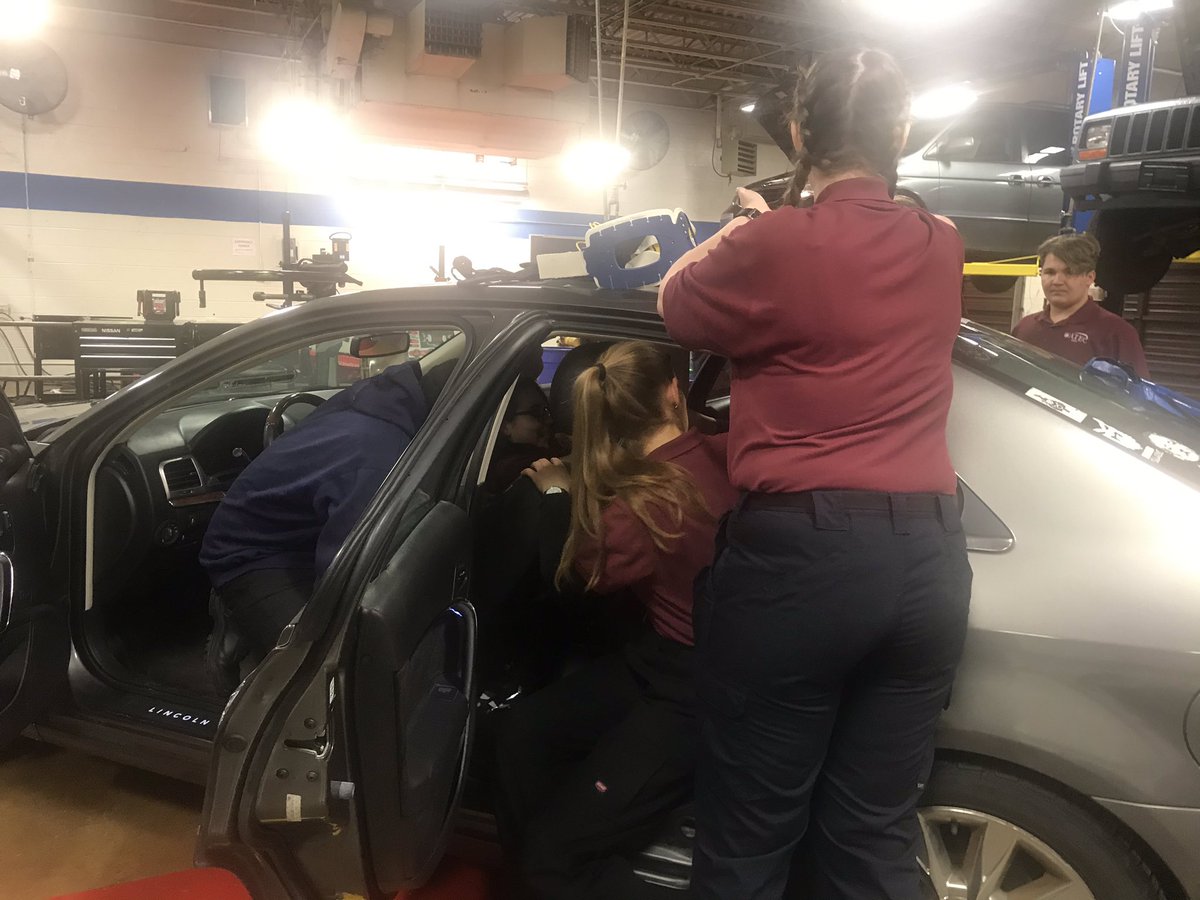 EMT students are practicing vehicle extrications with a simulated patient in the backseat.