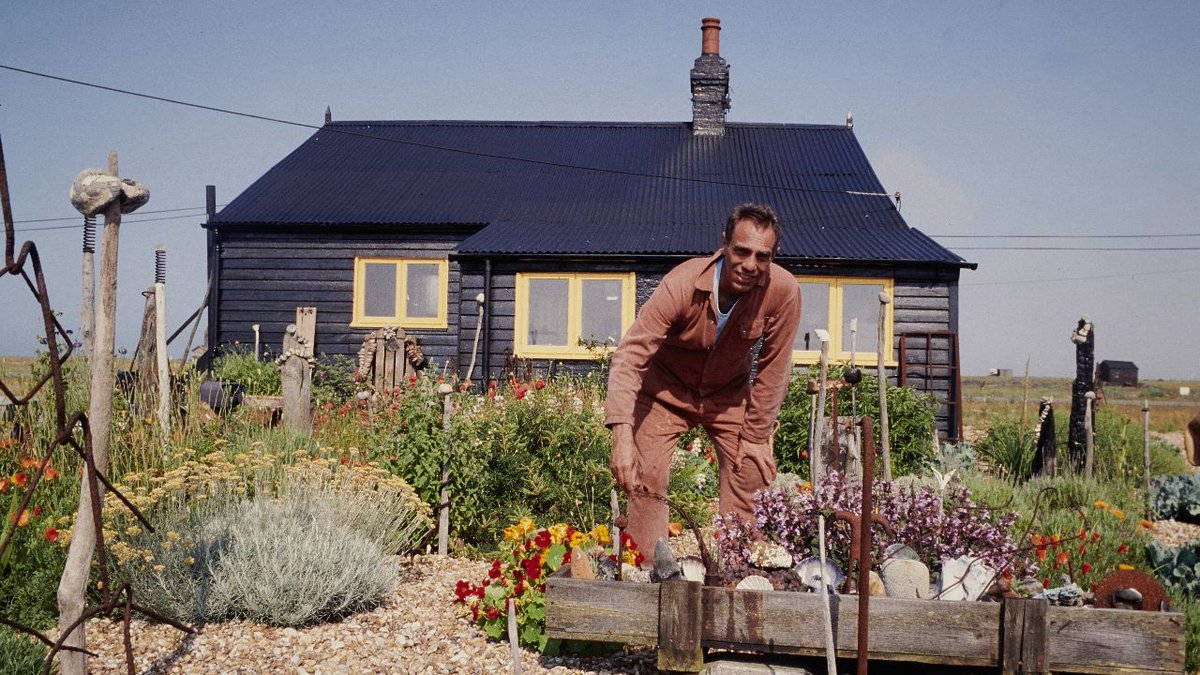 an image of Prospect Cottage with Derek Jarman standing outside bent towards the camera