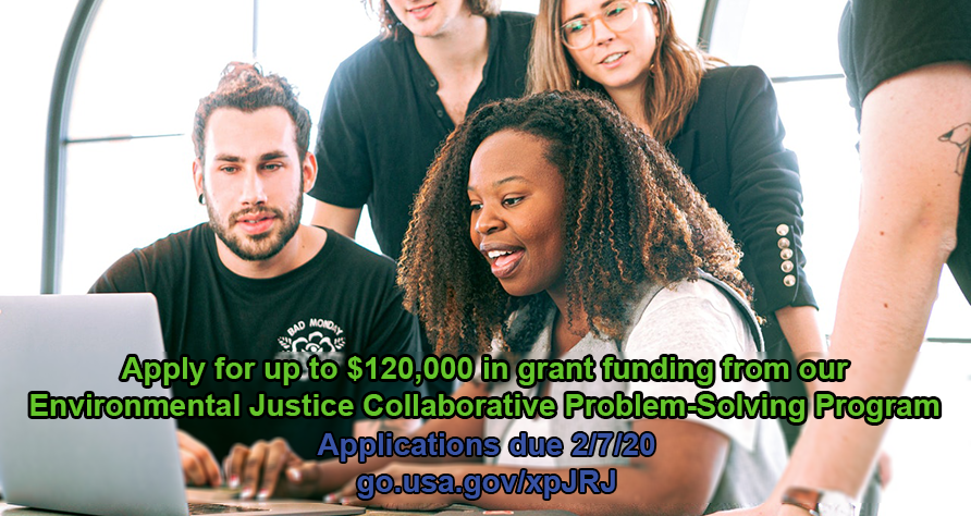 A diverse team of people gathered around a desk looking at a computer screen