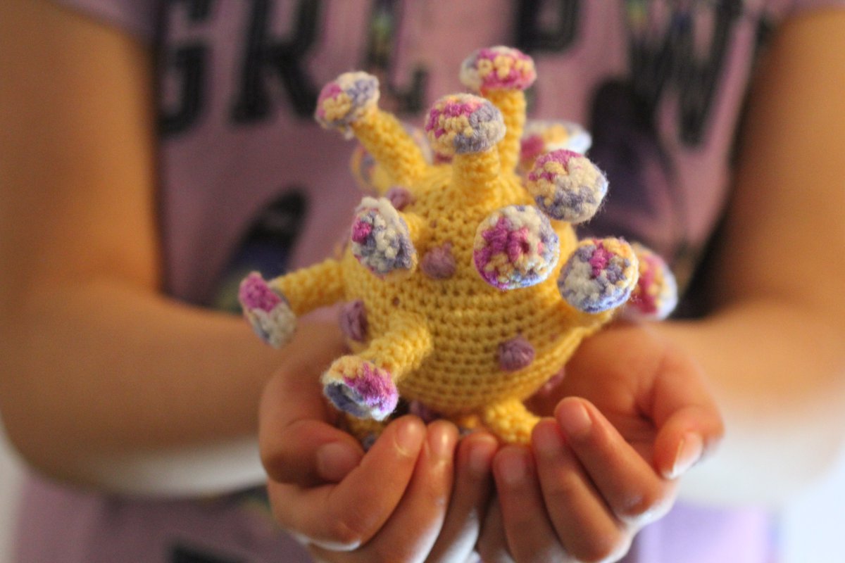 A kid holding crocheted coronavirus with both hands