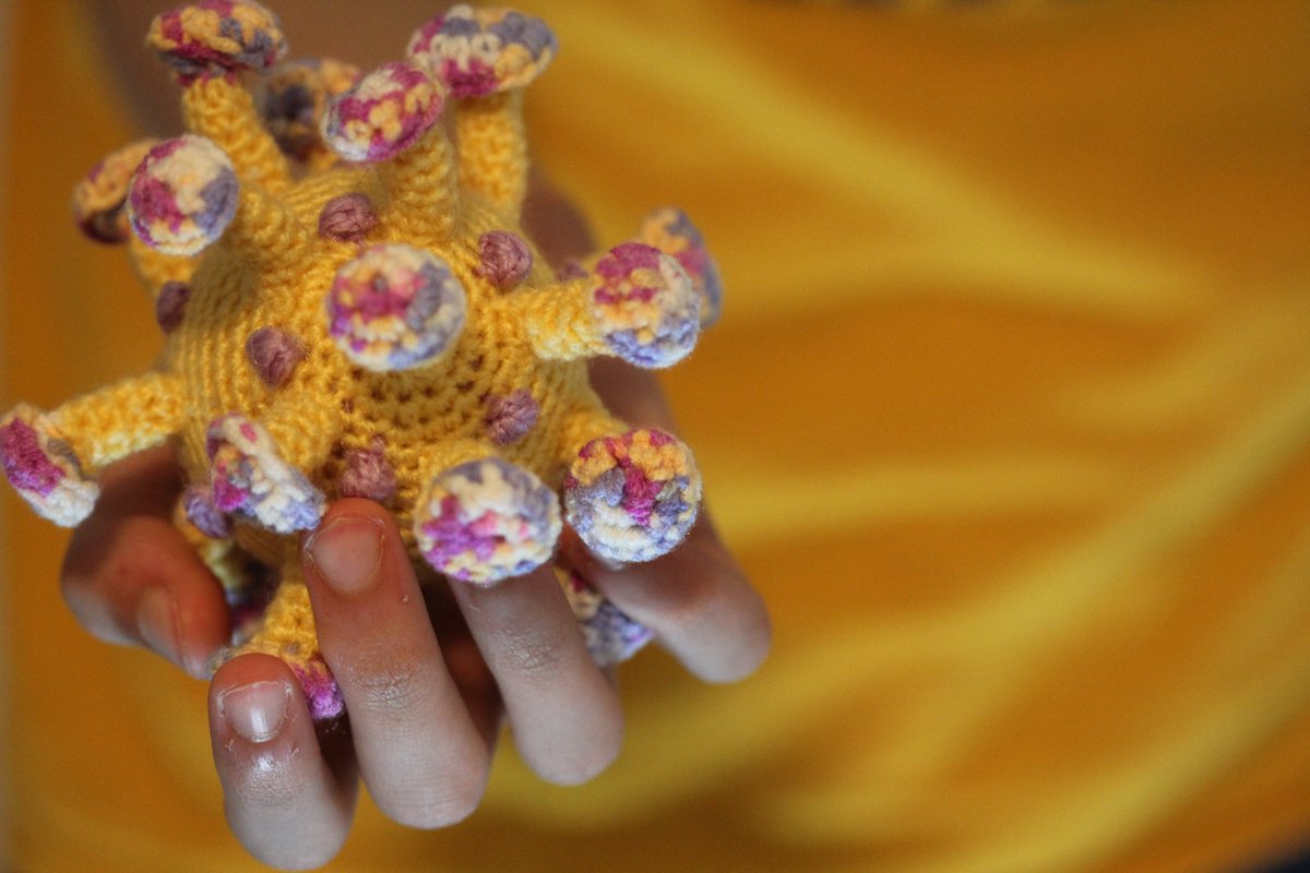 A kid holding crocheted coronavirus in hand