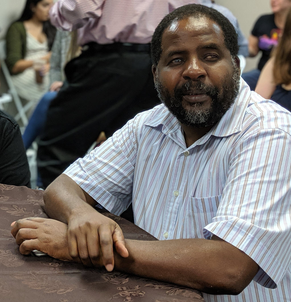 Martin Kieti, Bookshare Program Manager -Africa sits at a table and looks into the camera.