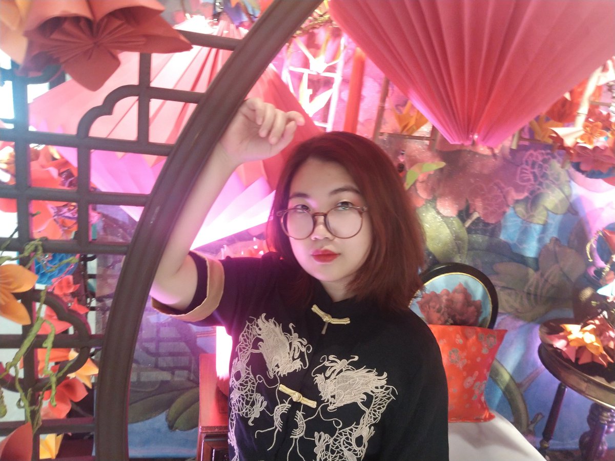 Person leaning against a trellis with lanterns in the background.