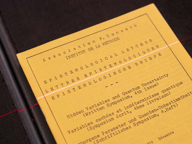 A yellowed journal cover that reads Epistemological Letters on a scanner bed with a red laser scanner over it