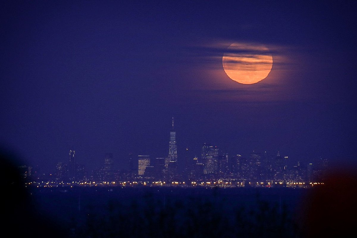 A snow moon shines brightly above the Manhattan skyline, as seen from New Jersey's shore. 