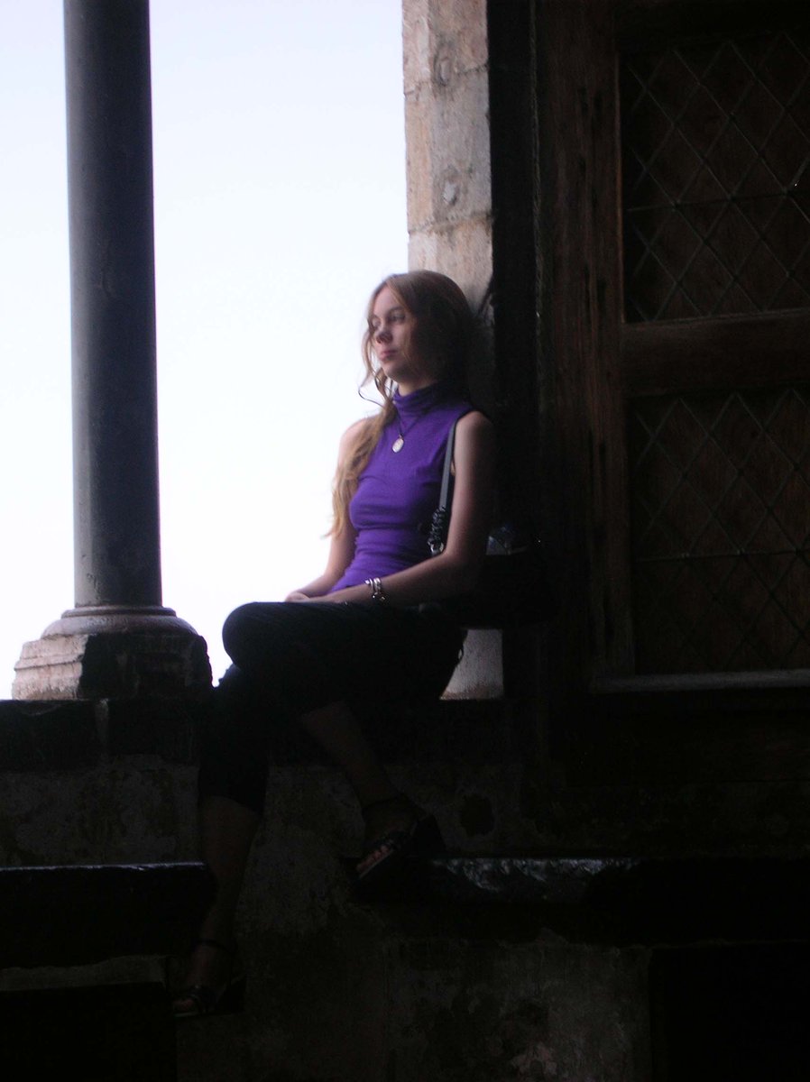 Casey at 17yo in purple shirt sitting in a castle window, gazing thoughtfully into distance.
