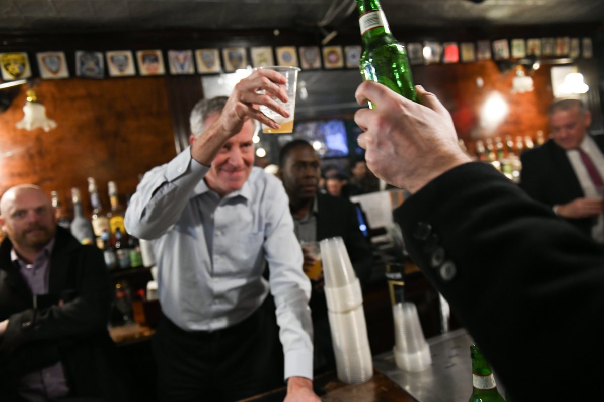 A photo of the Mayor doing a cheers with a man holding a bottle.