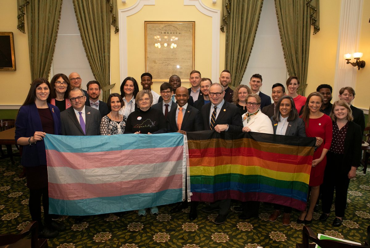 Group in front of trans and rainbow flag