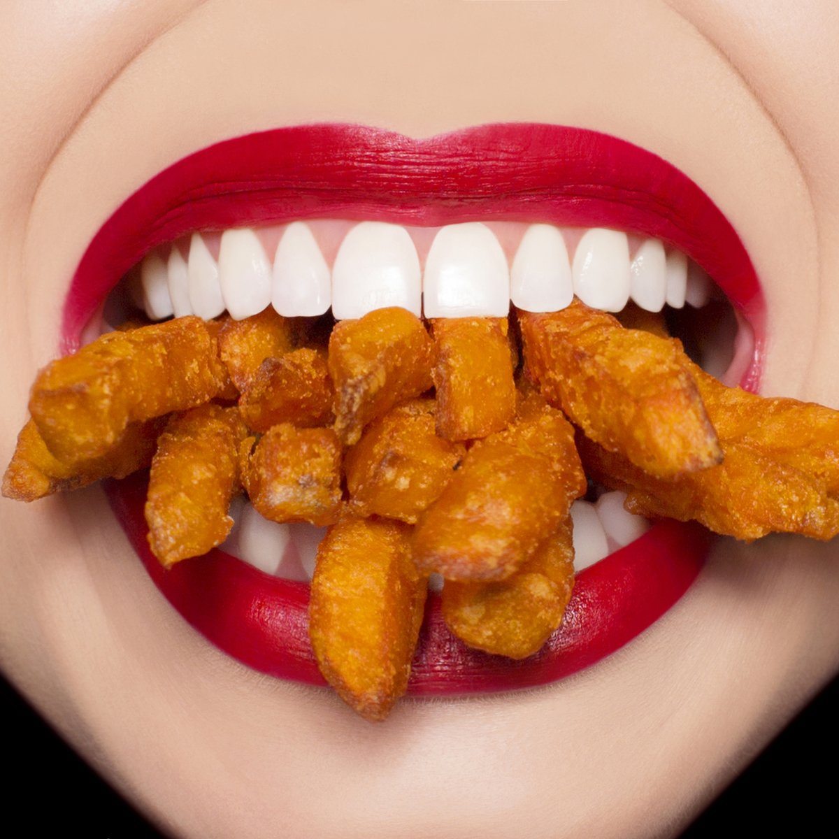 Photo of mouth full of sweet potato fries. 