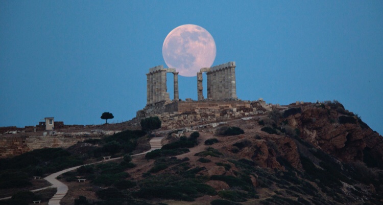 The full moon rises behind the columns of the ancient marble Temple of Poseidon at Cape Sounion, southeast of Athens, on the eve of the summer solstice on June 20, 2016. The temple located on a promontory at Cape Sounion, about 70km south-southeast of Athens, built 444 BC.