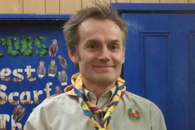 Steve Walsh wears a Scouts uniform featuring two twisted scarves and a beige shirt with badges