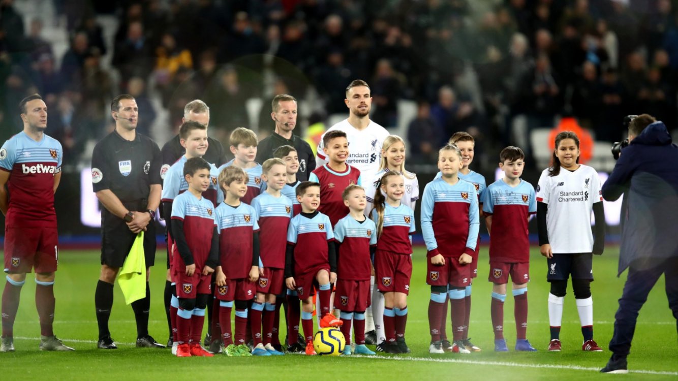 Varios niños posan con los jugadores antes de un partido en la Premier League.