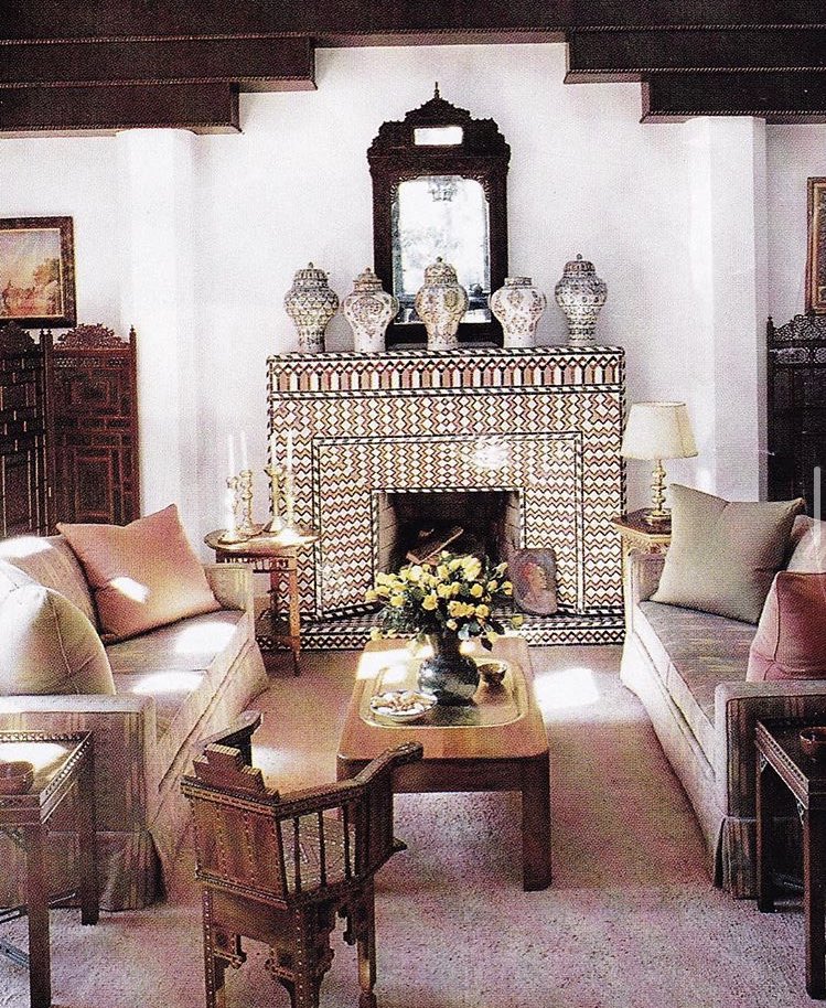 The salon is anchored by a traditional zellige mantelpiece (intricately patterned Moroccan enamel coated terracotta tile chips set into plaster) designed by Bill Willis, on which rests a collection of ancient pottery. Crisp white plaster walls and wood beams, a Jean Dunand -