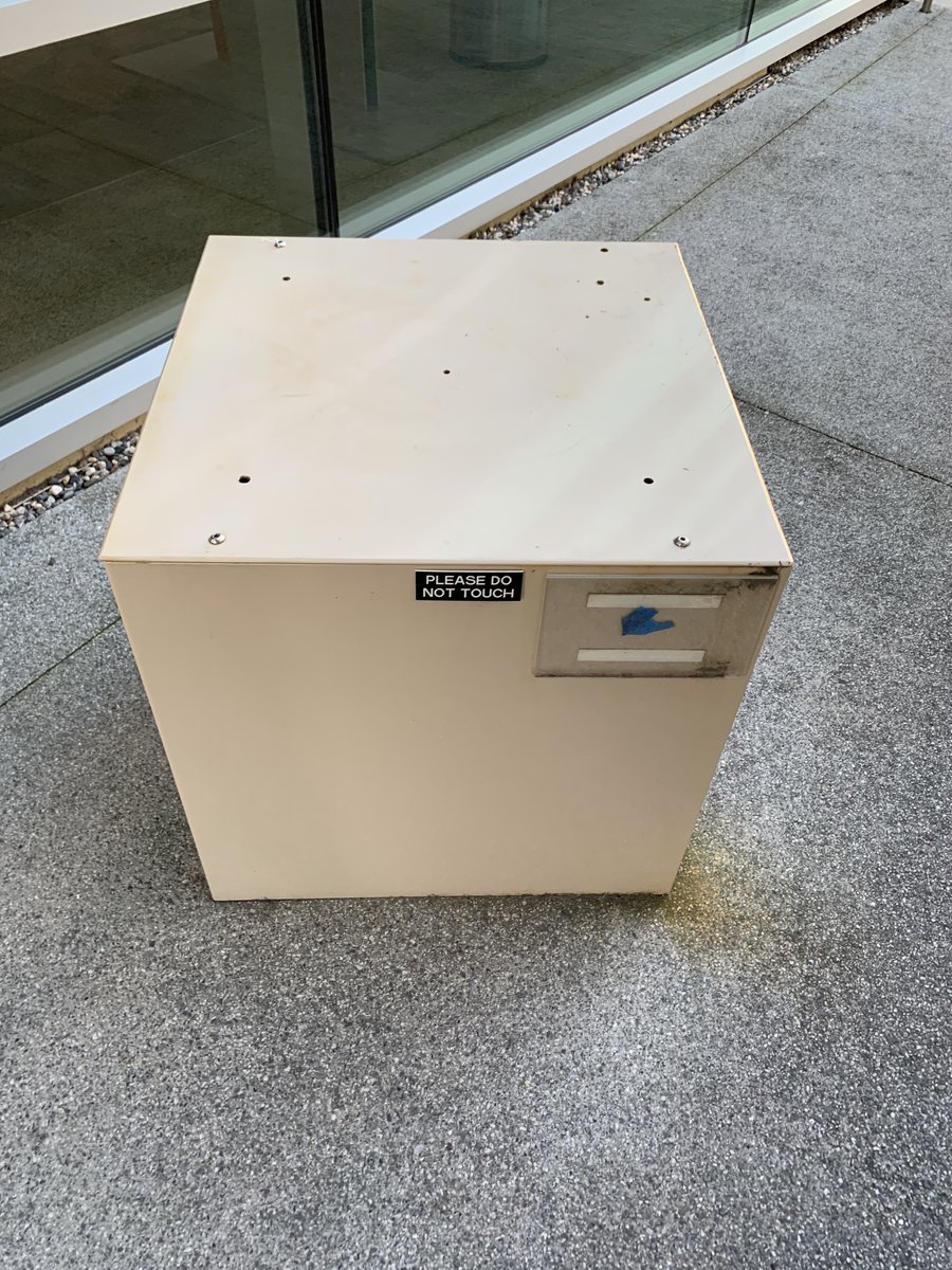 A metal box in the middle of a walkway between two buildings.