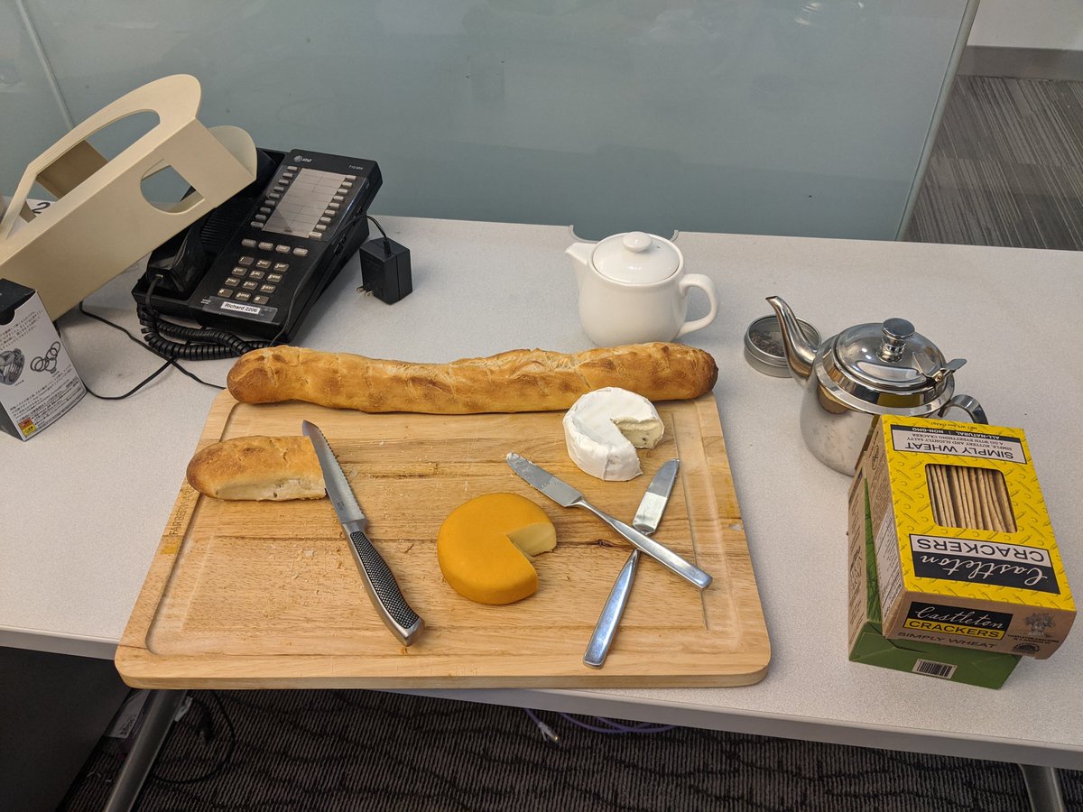 A tray of freshly baked baguettes, with brie and gouda. Also some crackers and tea.