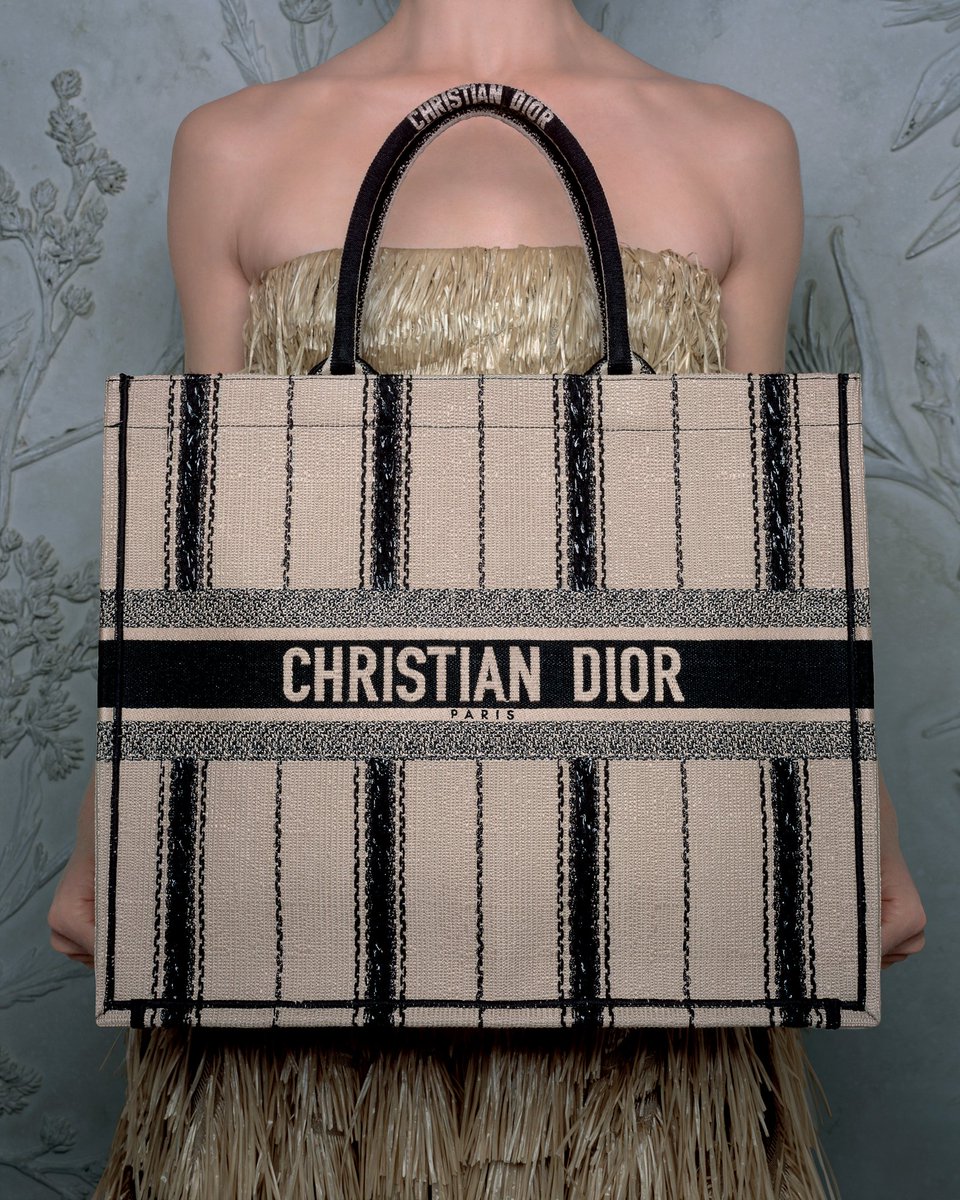 Dior's tweet image. For #DiorSS20, timeless House signatures are given a makeover by Maria Grazia Chiuri that speaks of pastoral pleasures, from the #DiorBookTote to the legendary #DiorBarJacket, floral embroideries to the straw hats, available now on.dior.com/ss20 and in boutiques worldwide.