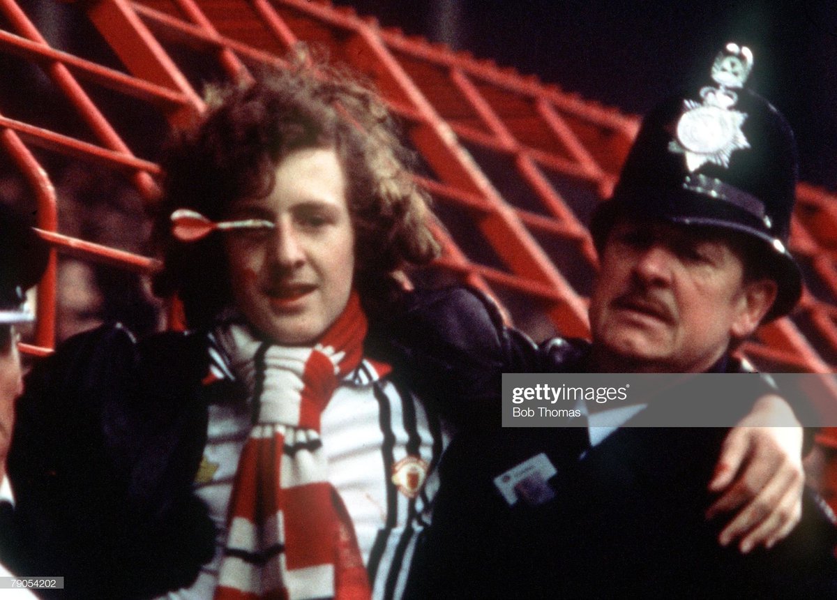 Peter Brookes, a Manchester Utd fan, being helped by the police after being struck in the face with a dart during a game against Liverpool at Anfield, Feb 1978.Photo by Bob Thomas