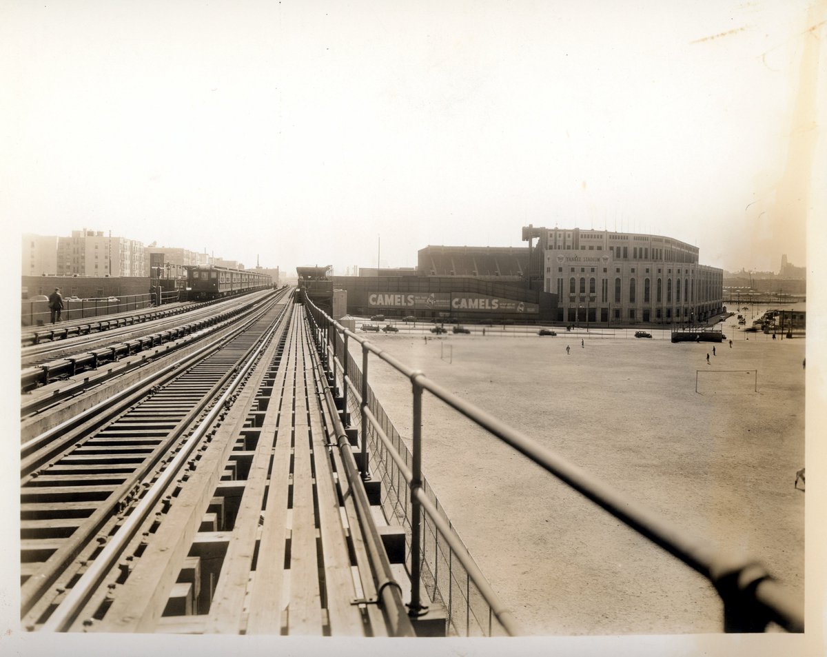 Yankee Stadium, Bronx, ca 1925 - A look at 161st Street Station tracks and platform on IRT Woodlawn Line heading towards Yankee Stadium. You can see the train sitting at the station stop and Camel cigarette ads on the back of the left field bleachers