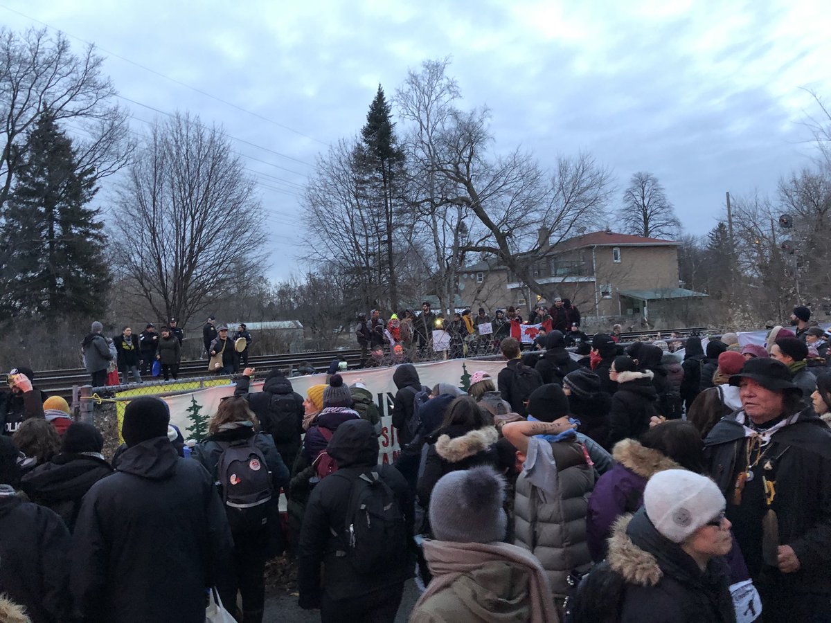patbonin's tweet photo. Des Premières nations &amp; des citoyen.nes en appuient bloquent une voie ferrée du CN à Toronto en solidarité avec la nation #Wetsuweten dont le territoire est encore envahi par la GRC &amp; #CoastalGaslink (TransCanada) sans leur consentement. #WetsuwetenStrong #reconciliation #polcan https://t.co/vGTMeoMUjH
