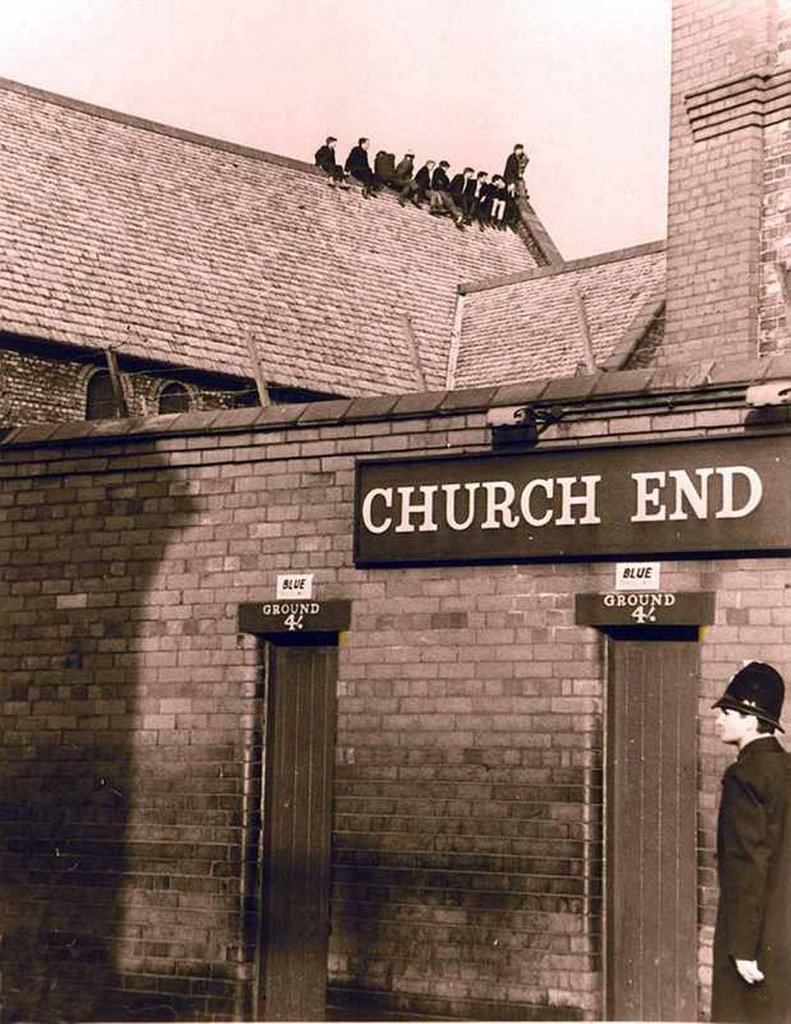 Everton fans taking in the game from the roof of the Church of St Luke the Evangelist, which sits in the corner of Goodison Park, 1960s.No image credit.