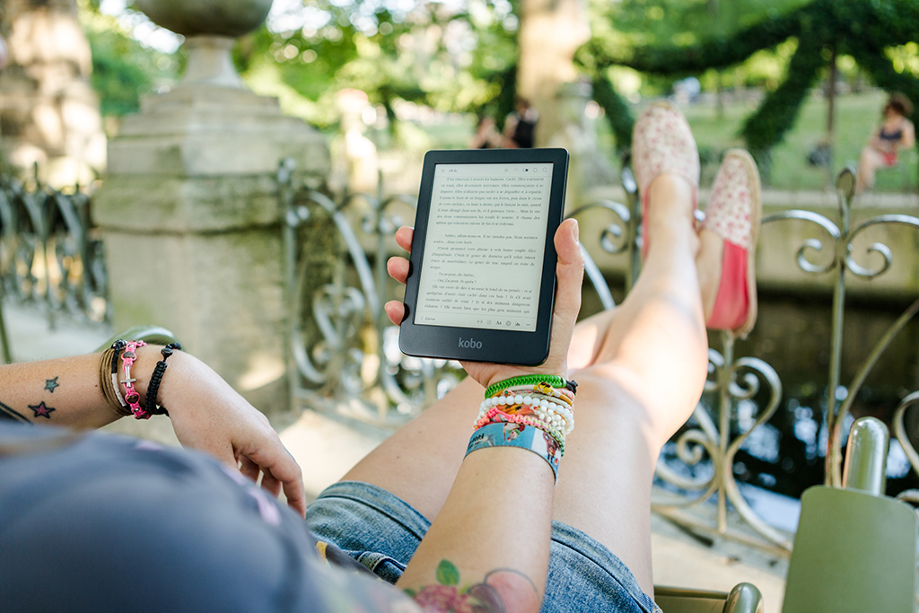 a woman laying in a hammock reading a tablet