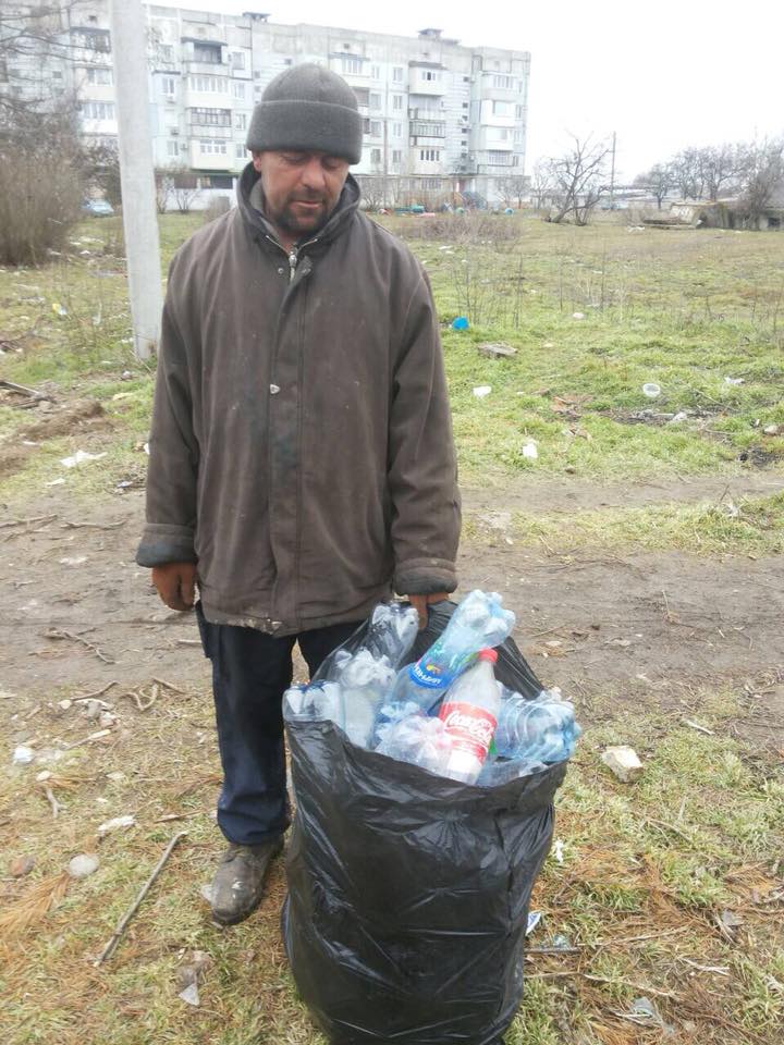 Бомж на мусорке. Бомж собирает бутылки.