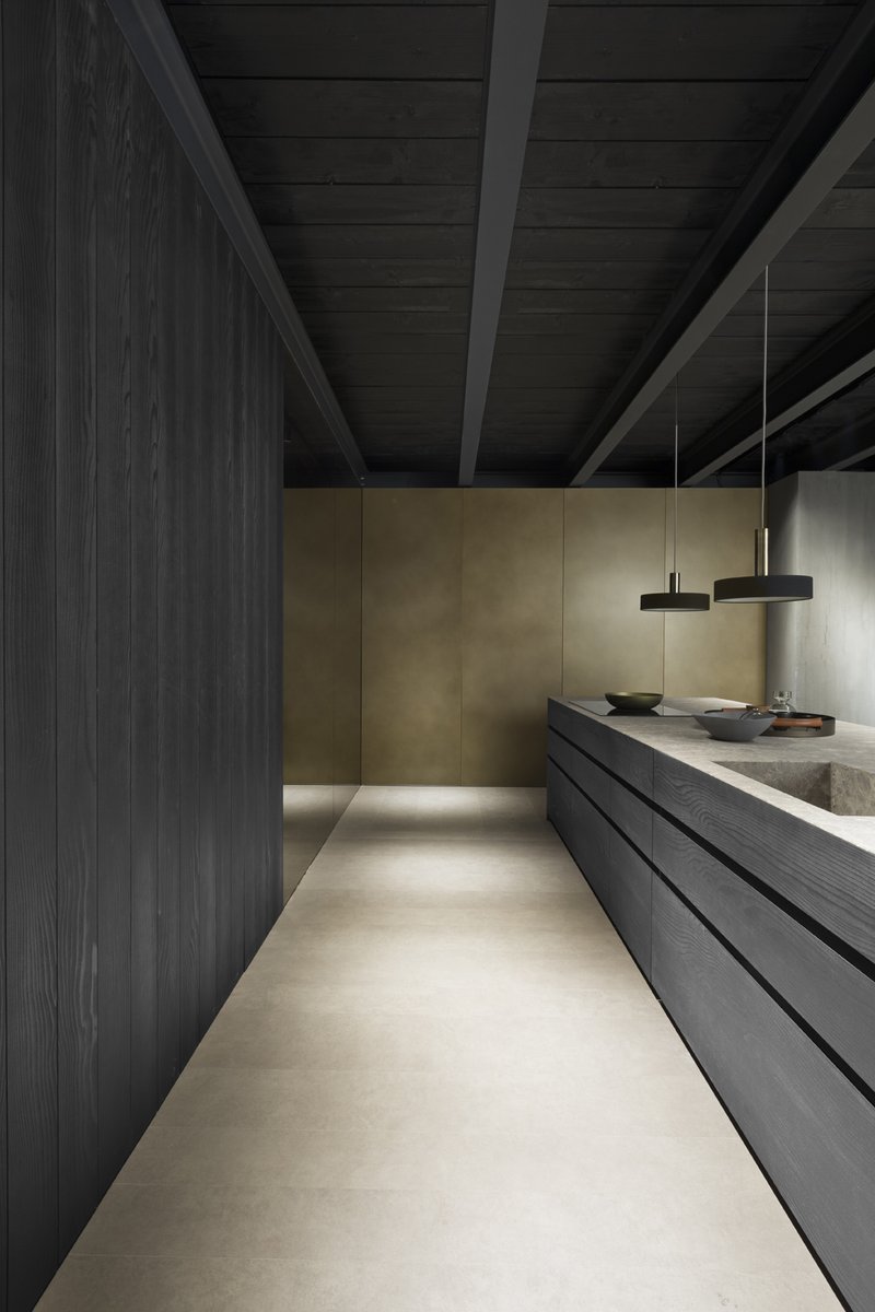 FLY | #kitchen A solid block in which thicknesses are reduced to a minimum to exalt the size of the island. Stained cedar wood, Emperador raw stone and bronze dust doors on the tall units create a decor featuring warm, refined colours. #modulnova #designkitchen #kitchen