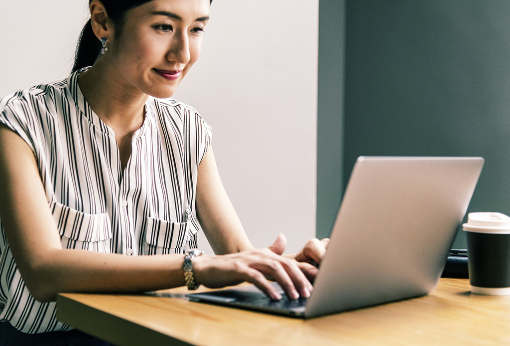 a smiling woman looking at her laptop