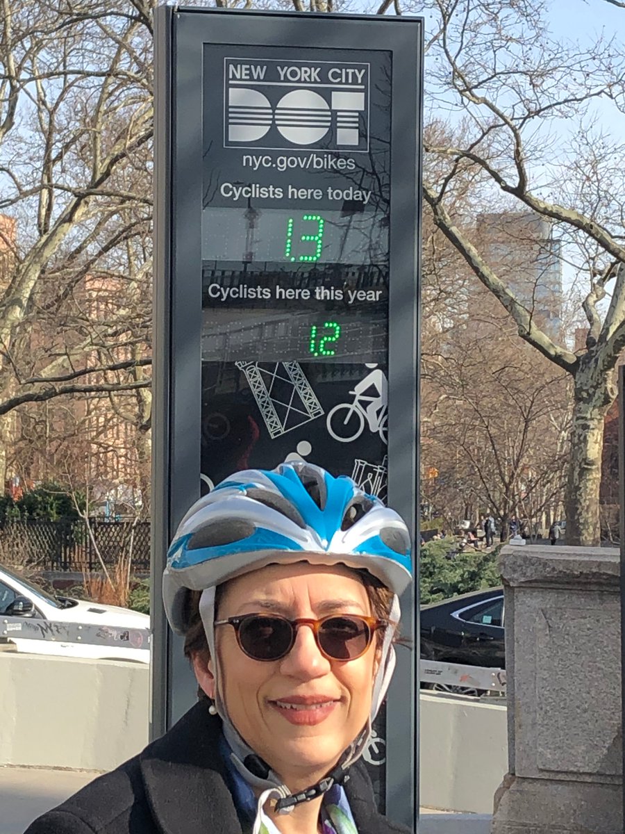 Commissioner Trottenberg stands in front of the Manhattan Bridge bike counter which shows she's the 1300th cyclist over the bridge today