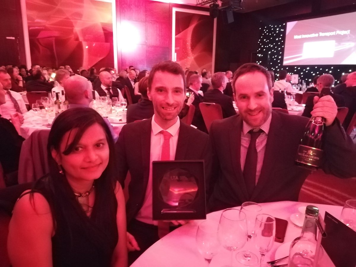 Winners holding the award, seated at a table