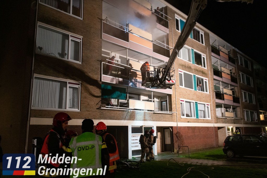 Acht woningen ontruimd na brand in kelderbox van flat in Hoogezand; brandweer haalt bewoners met hoogwerker uit woning..