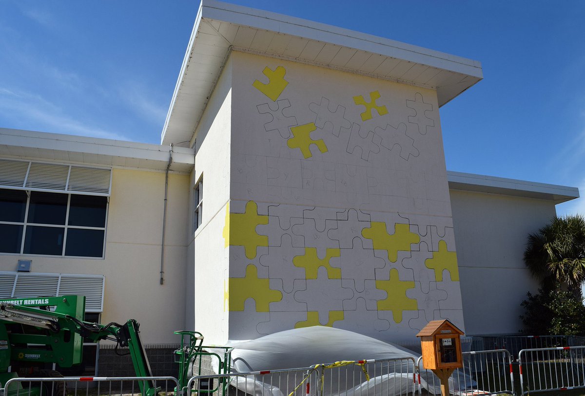 MyrtleBeachGov's tweet photo. Work is underway to create an autism-themed mural on the exterior wall of Crabtree Memorial Gym, facing Savannah's Playground. #MyrtleBeach staff member Aaron Frobase designed the puzzle-piece layout for the mural, and staff are gradually filling in the colors. https://t.co/IpEnlhEkS3