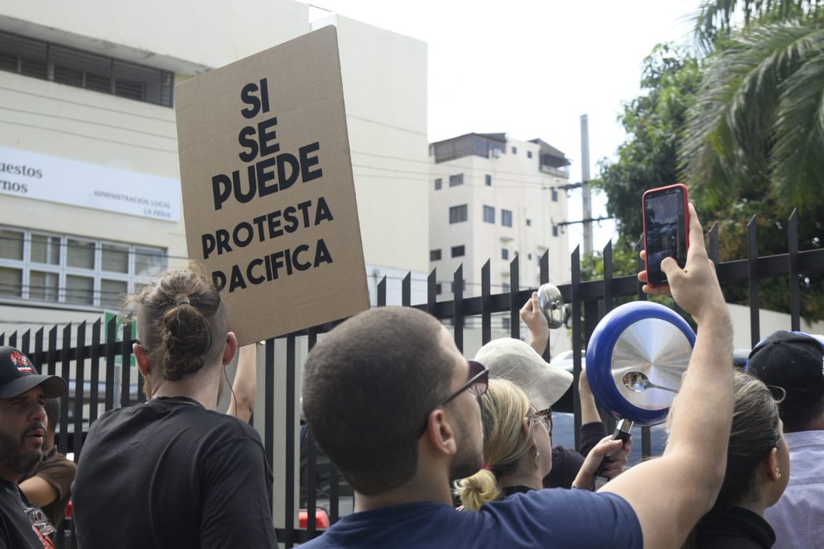 DiarioLibre's tweet photo. #ÚltimoMinuto: Unas quince  personas realizan "cacerolazos" frente al edificio de la Pontificia Universidad Católica Madre y Maestra (PUCMM), donde se realizará la tarde de este miércoles la reunión del Consejo Económico y Social con los partidos políticos. 

#DL #DiarioLibre https://t.co/yjk6PKACK8