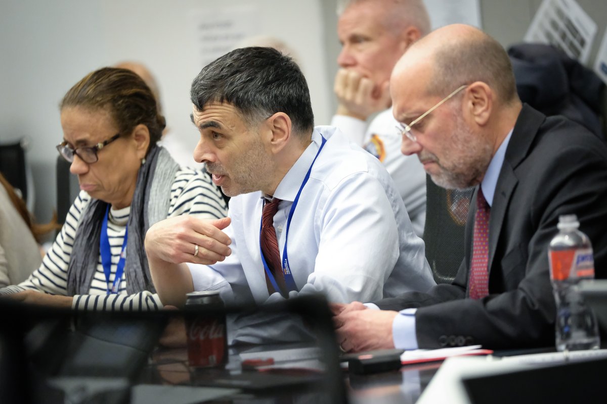 A photo of people sitting at a table speaking.