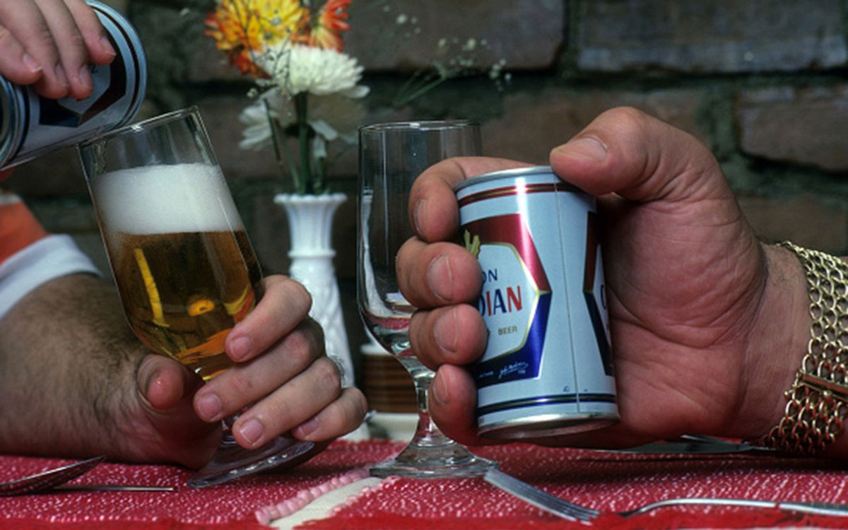 A regular sized can of beer, dwarfed by Andre's hand
