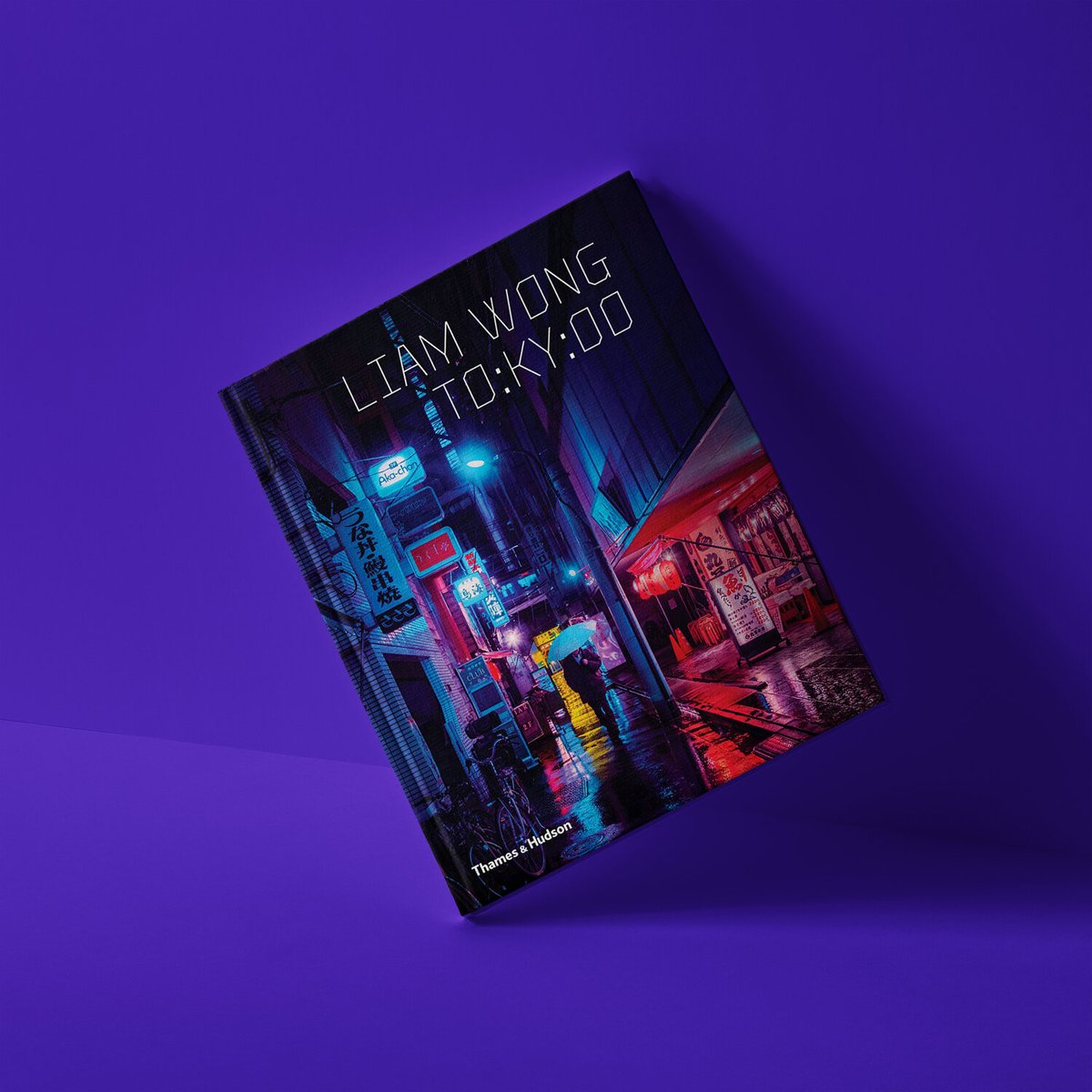 A photograph of the book, TO:KY:OO, capturing the beauty of Tokyo at night. The image on the cover is the first image in this post. It has a purple background and the book is angled.