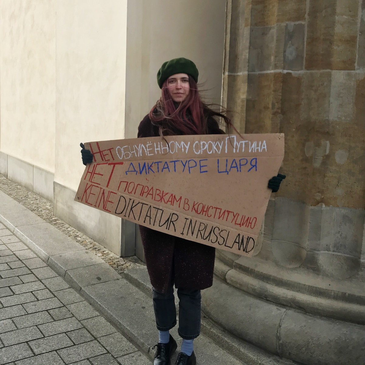 Ein Mensch mit Schild in einem der Bögen des Tores