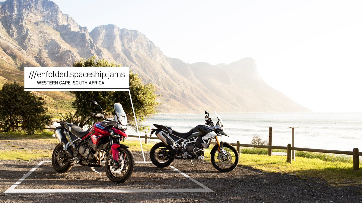 2 Triumph motorbikes stationed at ///enfolded.spaceship.jams in Western Cape, South Africa, by the ocean with a mountain backdrop