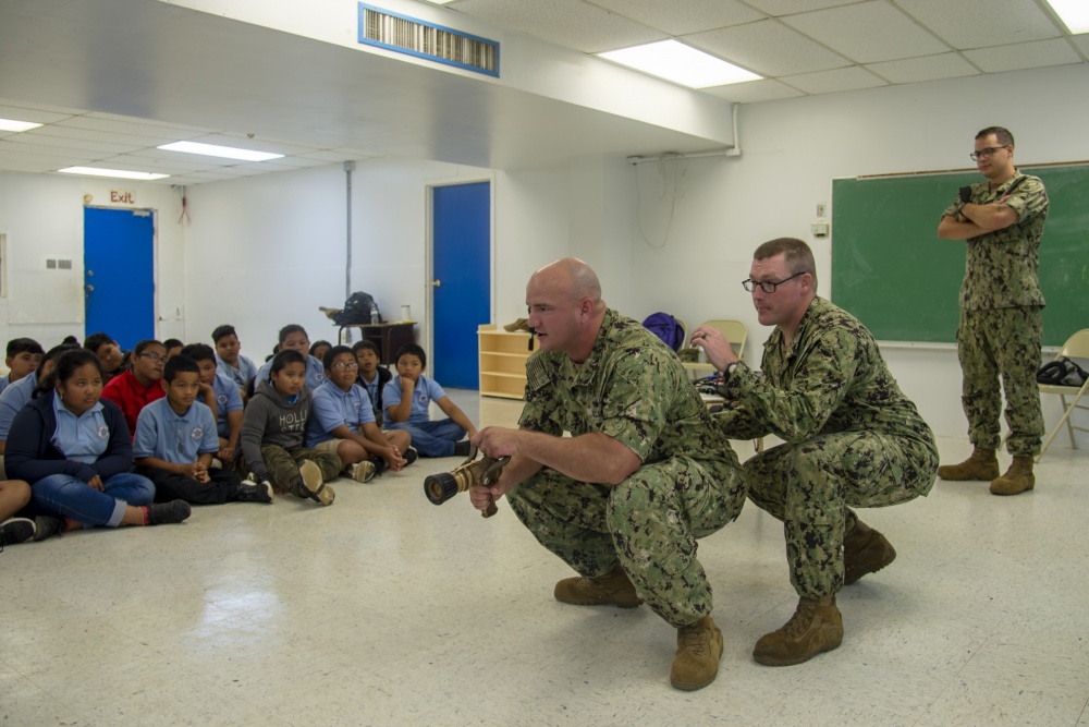 USPACOM's tweet photo. Submariners assigned to @PacificSubs Squadron Fifteen and Naval Submarine Training Center Pacific, Det. Guam, teach students about #firefighting during a career day at an elementary school. #CSS15 #ProfundeCogigate #FreeandOpenIndoPacific. https://t.co/5YYJE2oIqI