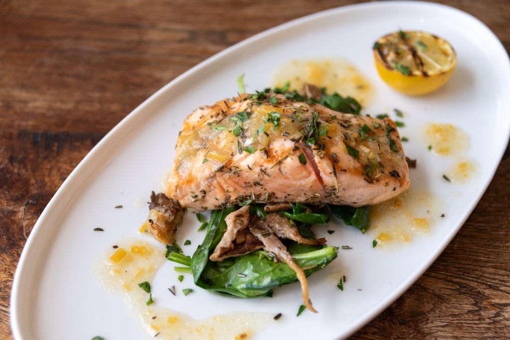 Join us for dinner and taste one of our delicious entrées, like this charred organic salmon served with roasted forest mushrooms, local spinach, yukon mash, and warm lemon vinaigrette.