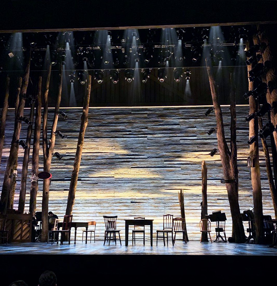 Come From Away stage with trees, tables, and chairs